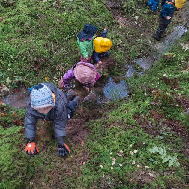 Kinder laufen im Gelände am Bachufer